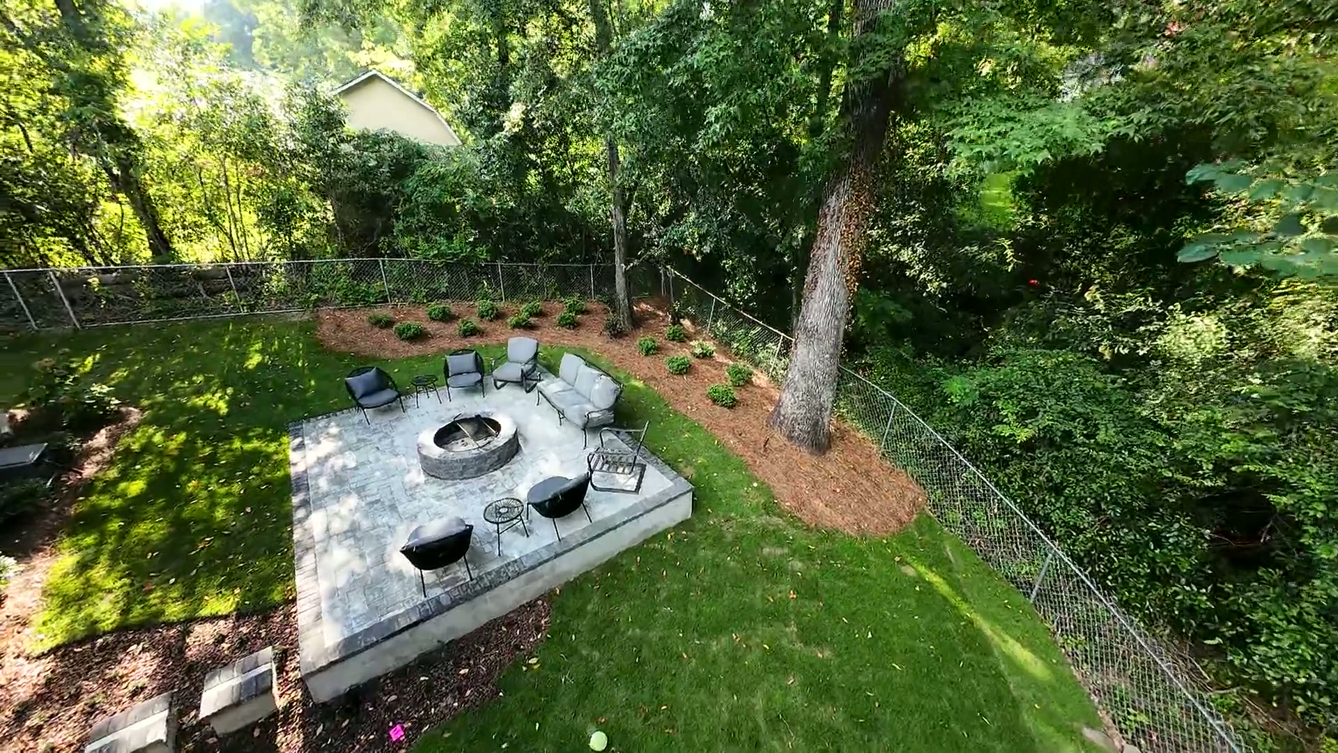 Aerial view of a Birmingham backyard with a stone fire pit patio, fresh landscape beds, and manicured lawn